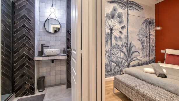 Un baño moderno con salpicadero de baldosas en espiga, un espejo redondo, un lavabo sobre encimera y un inodoro.