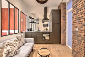A compact kitchen with a built-in oven, a gas stove, and a stainless steel range hood.