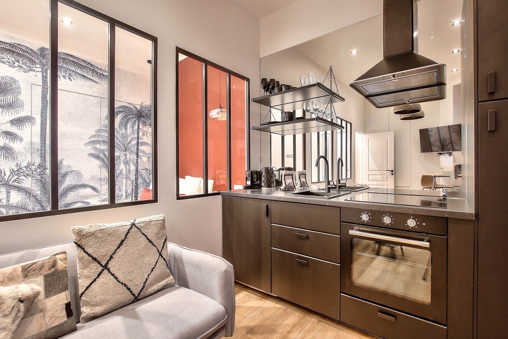 A modern kitchen with a built-in oven, a stainless steel range hood, and a glass-top island.