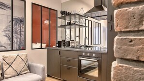 Una cocina moderna con horno empotrado, una zona de comedor con sofá y mesa, y una pared de acento de ladrillo.