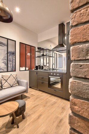 Une cuisine moderne dotée d’un four encastré, un coin repas avec un canapé et une table, et un mur d’accent en briques.