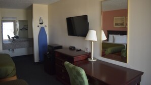 A hotel room with a bed, a desk, a chair, a TV, a lamp, a mirror, and a dresser. - Royal Inn (Springdale)