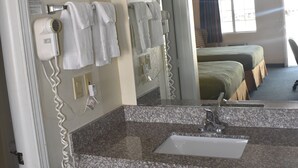 A hotel bathroom with a sink, towel rack, and a hairdryer. - Royal Inn (Springdale)
