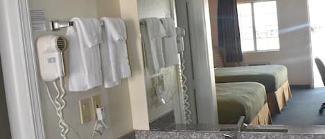 Un baño de hotel con lavamanos, perchero para toallas y secador de pelo.