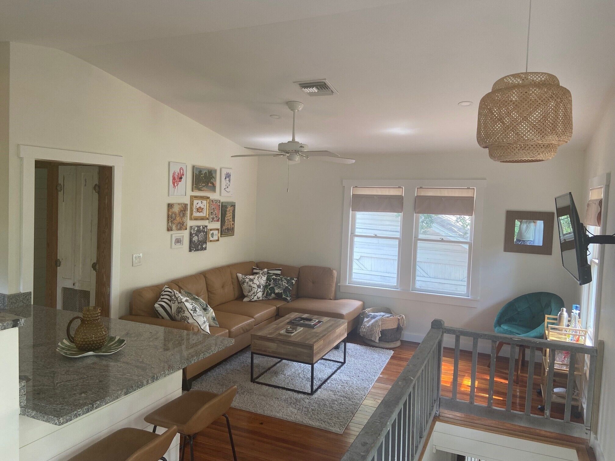 A modern living room with a brown leather sofa, a coffee table, and a dining area with a granite countertop.