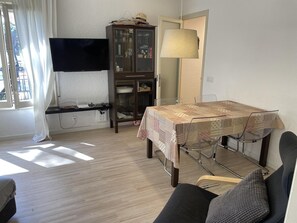 Un salon comprenant un téléviseur, un meuble, une table à manger et un canapé.