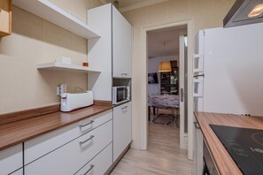Uma cozinha moderna com armários brancos, micro-ondas e torradeira.