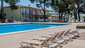 A swimming pool with lounge chairs and a building with balconies.