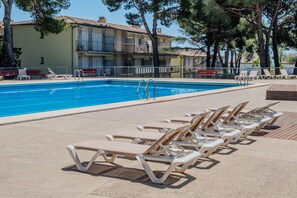 A swimming pool with lounge chairs and a building with balconies.