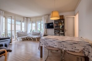 A modern living room with a sofa set, a dining table with chairs, a TV, and a cabinet.