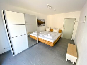 Un dormitorio moderno con una cama, un armario, una mesita de noche y un cuadro en la pared.