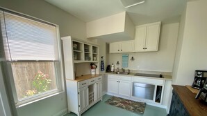 A kitchen with white cabinets, a built-in oven, and a window with blinds.