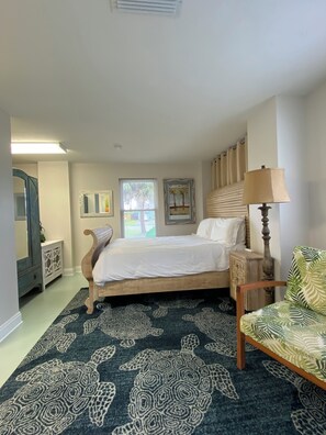A bedroom with a bed, a chair, a lamp, a dresser, and a window with blinds. - Walk To The Beach At Beacon Hill. (Port St. Joe)