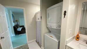 A laundry room with a washing machine, dryer, and a small sink with a mirror.