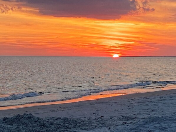 Una playa con un atardecer sobre el océano.