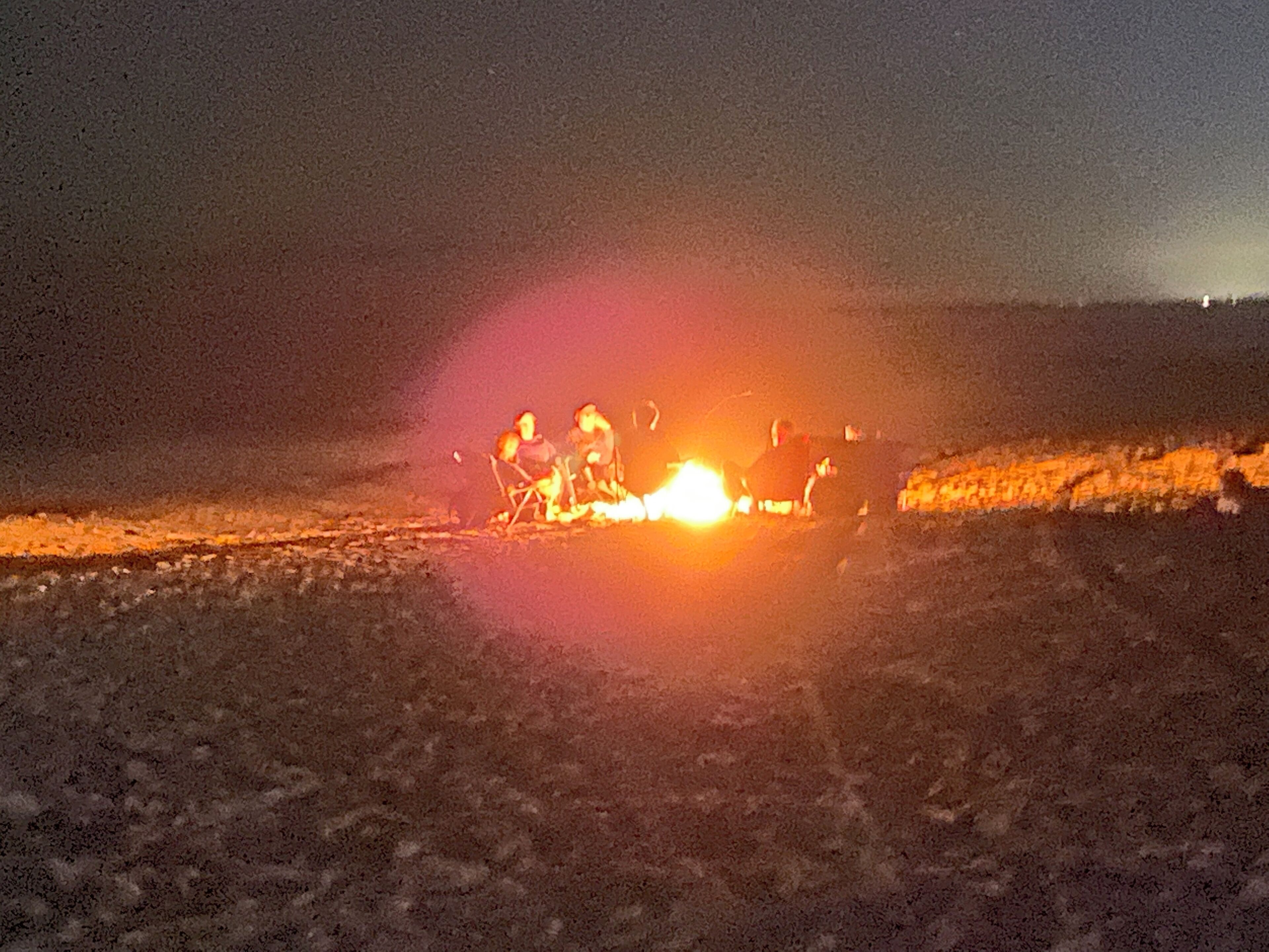 A group of people gathered around a campfire at night.