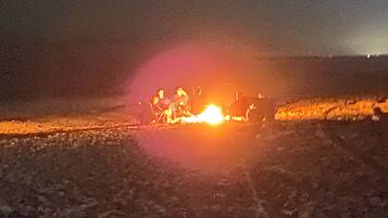 A group of people gathered around a campfire at night.
