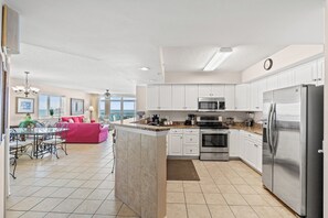 A modern kitchen with white cabinets, stainless steel appliances, and a dining area with a red sofa and a table.