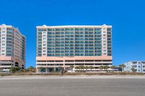A multi-story hotel with a large number of rooms, a parking garage, and a flat roof.