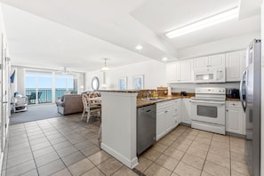 Uma cozinha espaçosa com armários brancos, uma ilha central e um espaço de refeições com vista.