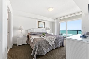 Une chambre à coucher comprenant un lit, des tables de chevet, un bureau et une grande fenêtre donnant sur un beau paysage.