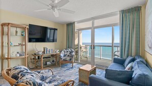A living room with a sofa, a chair, a television, and a bookshelf. - Crescent Keyes 807-Oceanfront 1BR/1BA (North Myrtle Beach)