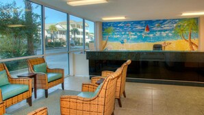 A lobby with wicker furniture, a large window, and a mural of a beach scene. - Crescent Keyes 807-Oceanfront 1BR/1BA (North Myrtle Beach)