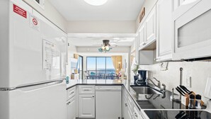 Une cuisine compacte avec des meubles blancs, un lave-vaisselle et une vue sur l’extérieur.