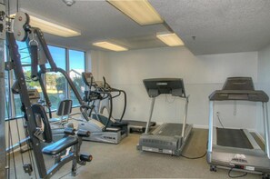 Un gimnasio con máquinas de cardio, una cinta de correr y una bicicleta estática.