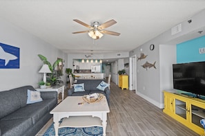 A modern living room with a grey sofa, a white coffee table, and a ceiling fan.