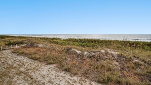 A sandy beach with sparse vegetation and a clear blue sky. - Nautical Watch 207-1BR/1BA Oceanfront condo in Windy Hill (North Myrtle Beach)