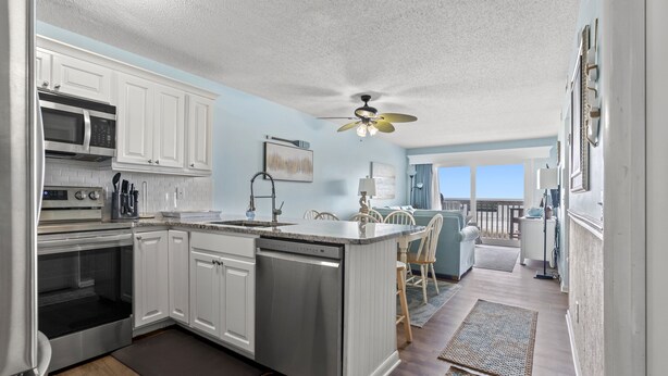 A modern kitchen with white cabinets, stainless steel appliances, and a central island. - Ocean Garden Villas C2-2BR/2BA Oceanfront Condo in Crescent Beach (North Myrtle Beach)