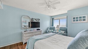 A bedroom with a bed, dresser, television, and a ceiling fan. - Ocean Garden Villas C2-2BR/2BA Oceanfront Condo in Crescent Beach (North Myrtle Beach)