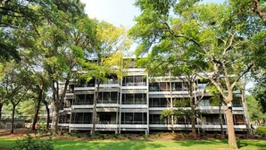 A multi-story building with a modern architectural design, surrounded by trees and a well-maintained lawn.