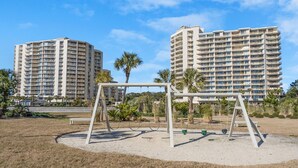 A playground with swings in front of a high-rise building.