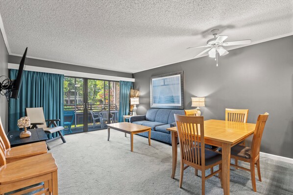 Relax in this inviting living room with a comfortable sofa, dining table, and ceiling fan.