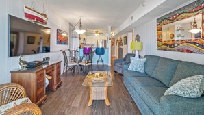 Un salón amplio con un sofá grande, una mesa de centro de vidrio y un comedor con sillas y una mesa.
