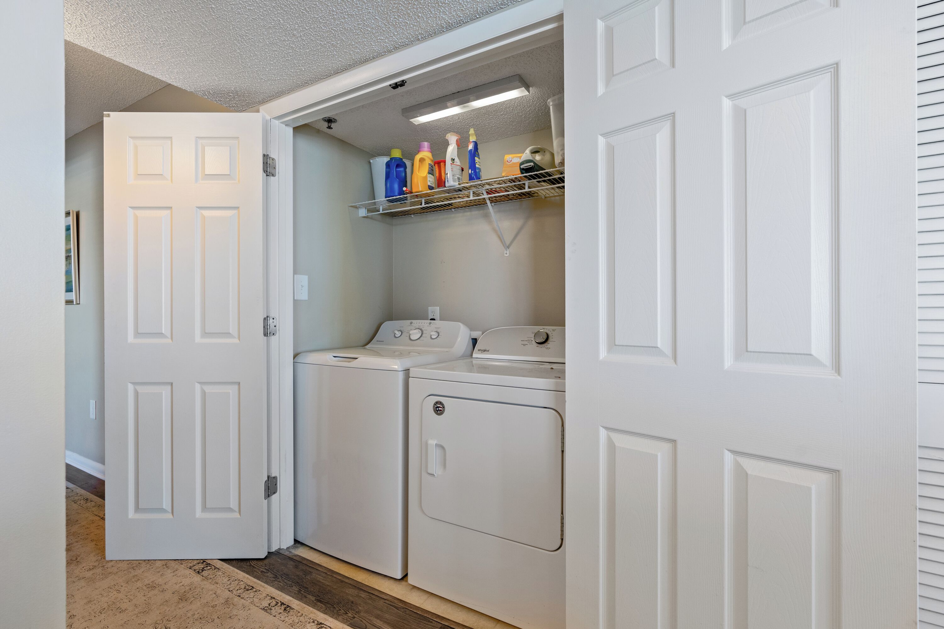 A laundry room with a washing machine, dryer, and a shelf with cleaning supplies.