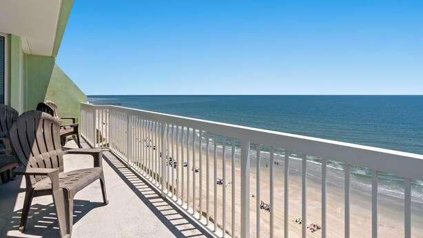 Un balcone con vista sulla spiaggia, sedie e una ringhiera.