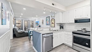 A modern kitchen with white cabinets, a stainless steel dishwasher, and a built-in oven.