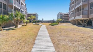 A pathway leading to a modern building complex with multiple balconies and a clear sky. - Tilghman Beach & Racquet Club 264-3BR/2.5BA Condo IN Ocean Drive (North Myrtle Beach)