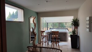 A modern kitchen with a large window, a hot tub, and a dining area with wicker chairs. - La Pépite des Tours (Châteaurenard)