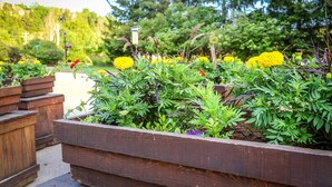 A garden with various plants and flowers, wooden planters, and a pathway. - The MountainSide by Escapades Tremblant (Mont-Tremblant)