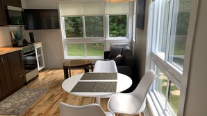 A modern kitchen with a dining area, large windows, and a view of greenery. - The MountainSide by Escapades Tremblant (Mont-Tremblant)
