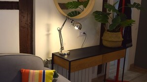 A modern living room with a grey sofa, a round mirror, a desk with a lamp, and a potted plant. - Cozy Studio st Level in the Very Center of Madrid (Madrid)