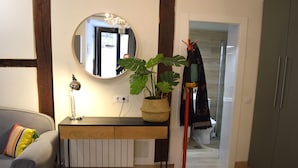 A room with a wooden console table, a potted plant, a mirror, and a red coat rack. - Cozy Studio st Level in the Very Center of Madrid (Madrid)