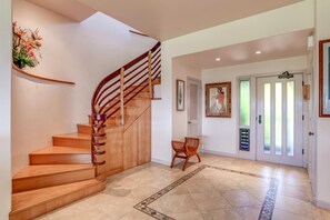 Un escalier en bois avec une rampe, une chaise et une porte dotée de panneaux en verre dépoli.