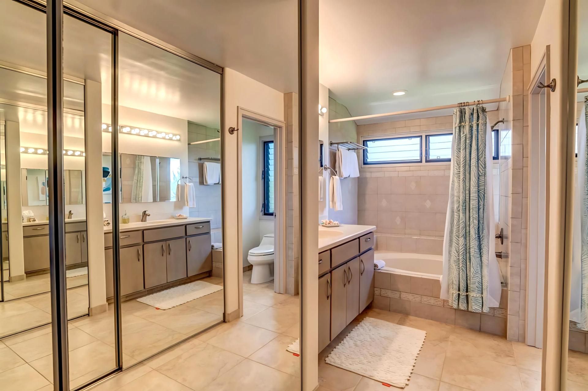 A modern bathroom with a glass-enclosed vanity, a separate shower area, and a bathtub.