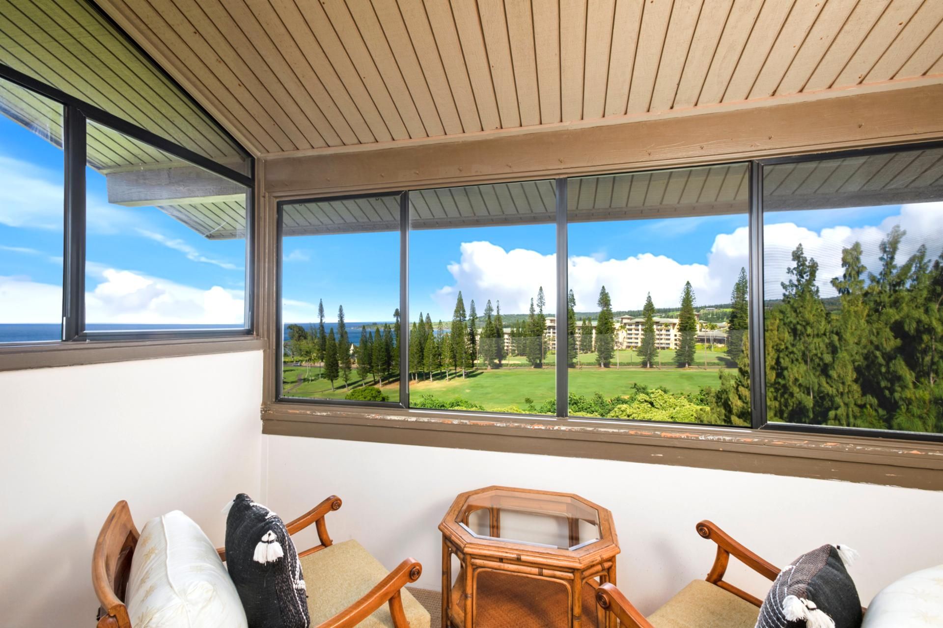 Un balcón con vistas a un campo de golf, sillas de madera y una mesa hexagonal.