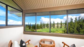 Un balcón con vistas a un campo de golf, sillas de madera y una mesa hexagonal.